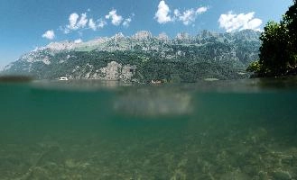 Under-and-over shot of Lake Walen showing the Churfirsten, Swiss Alps, aquatic, underwater, switzerland, under-and-over, rocks, surface, bed, mountains, walensee, alps, walen, churfirsten, lake, tuquoise, mols, teal, walenstadt, green