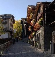 Geranium-infested street in Zermatt, autumn, outdoors, exterior, street, barn, chalet, cabin, house, tourism, zermatt, blue sky, switzerland, sunshine